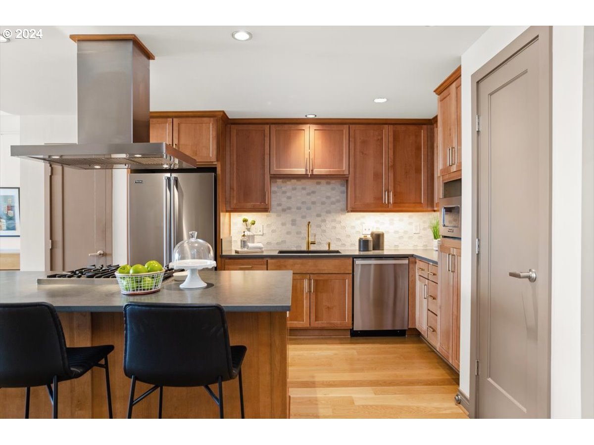 2454 Northwest Westover Road, Unit 5205 Portland, OR 97210 - Photo 14 of 33 a kitchen with stainless steel appliances kitchen island granite countertop a sink and cabinets