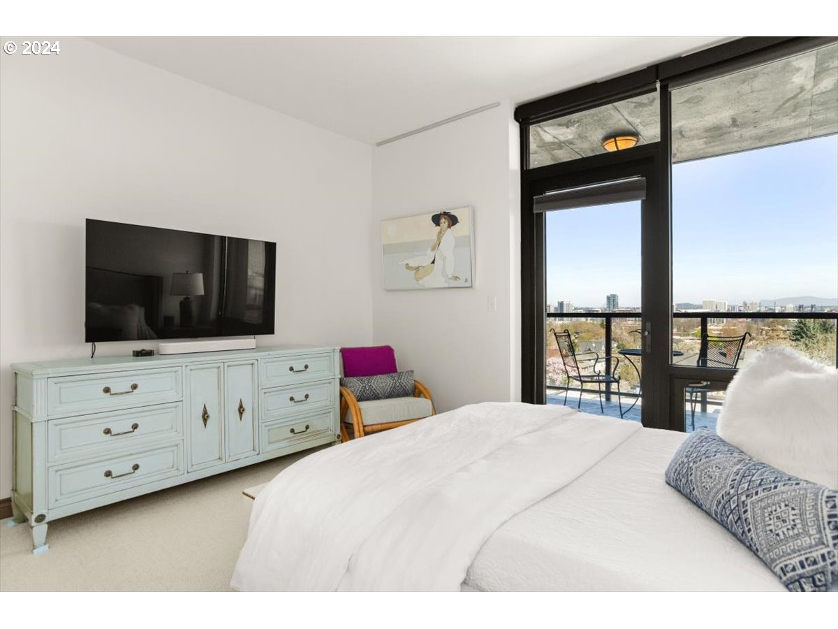 2454 Northwest Westover Road, Unit 5205 Portland, OR 97210 - Photo 18 of 33 a bedroom with a large bed and a flat tv screen on dresser next to a window