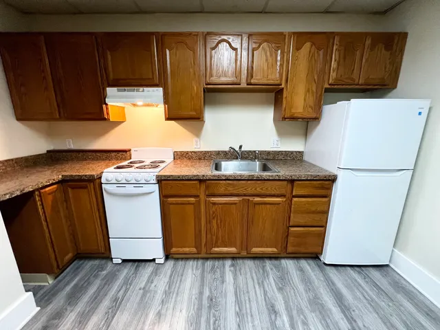 a kitchen with a refrigerator a stove and wooden cabinets
