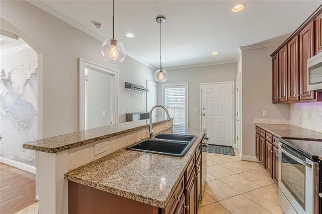 a kitchen with stainless steel appliances granite countertop a refrigerator a sink a stove a dining table and chairs