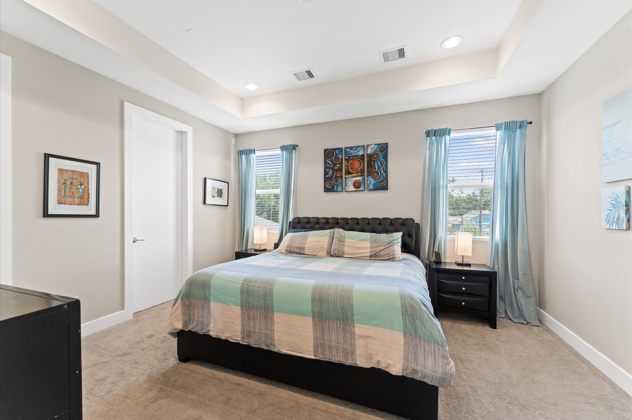 2422 Cochran Street Houston, TX 77009 - Photo 18 of 31 The 2nd-floor primary suite rests under a tray ceiling with recessed lighting. With two corner windows, the space provides the perfect setup for a large bed in between them without losing space for other bedroom furniture.