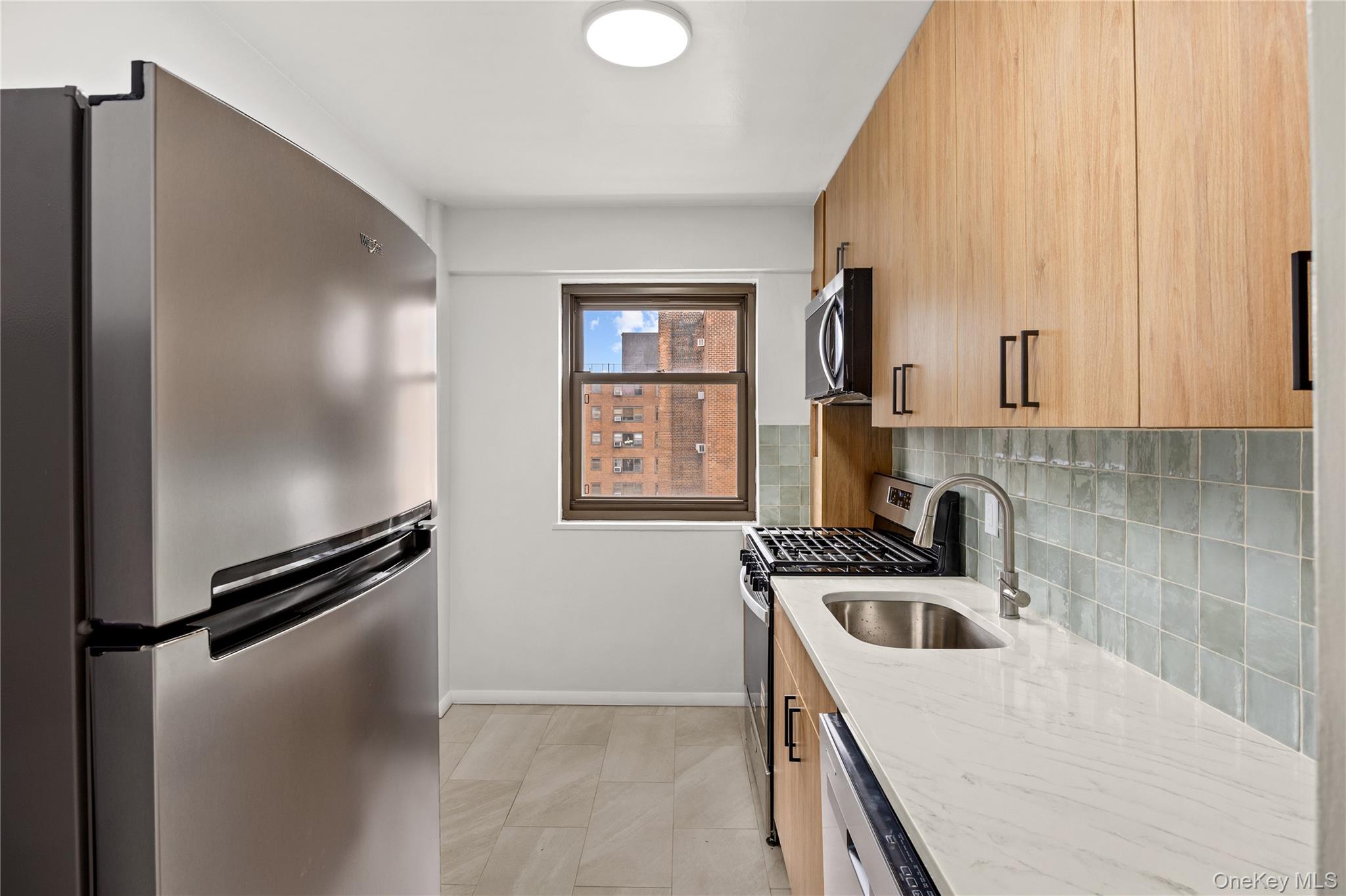 21-66 33rd Road, Unit 12B Queens, NY 11106 - Photo 12 of 23 a kitchen with a sink a refrigerator and cabinets