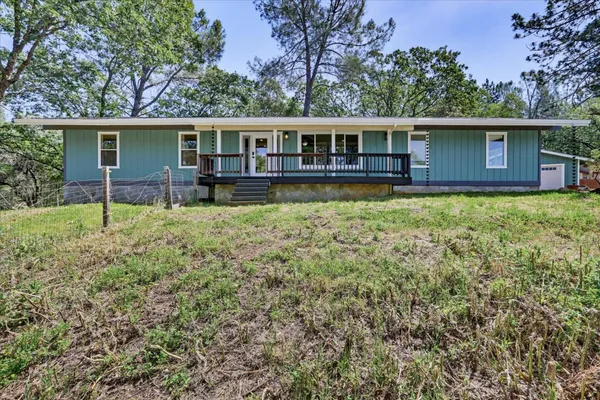a front view of house with yard and trees in the background