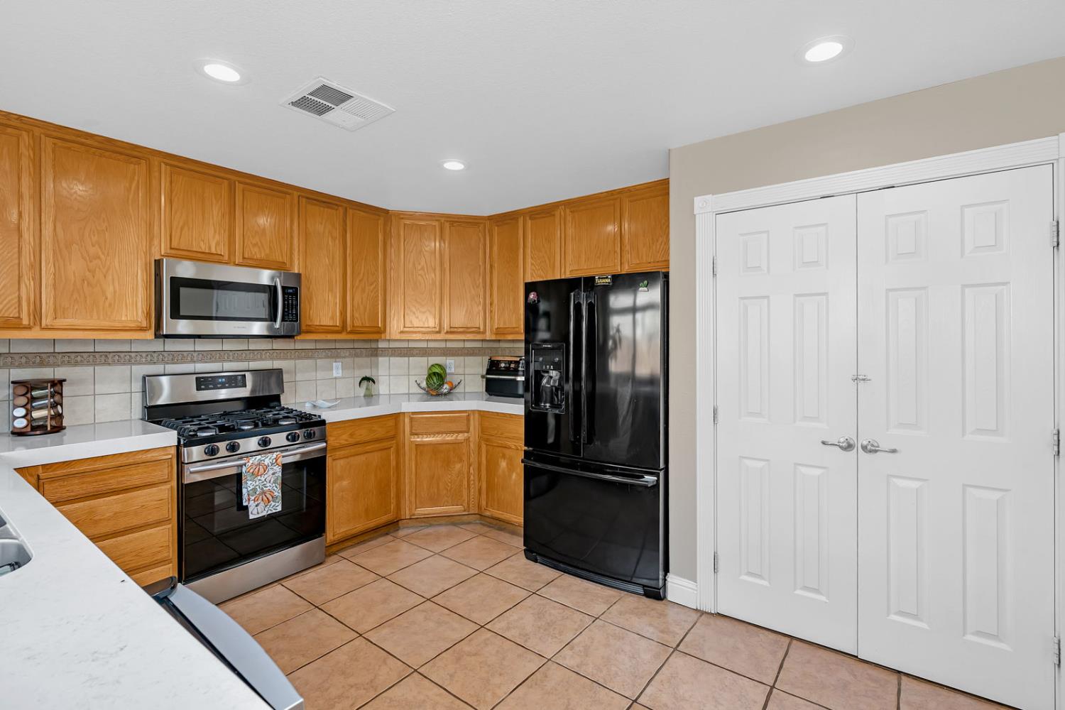 1406 San Rafael Street Los Banos, CA 93635 - Photo 14 of 35 a kitchen with a refrigerator a stove top oven a sink and dishwasher