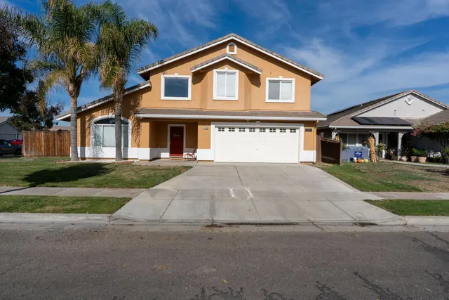 a front view of a house with a yard and trees
