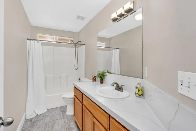 a bathroom with a granite countertop sink a mirror a vanity and shower