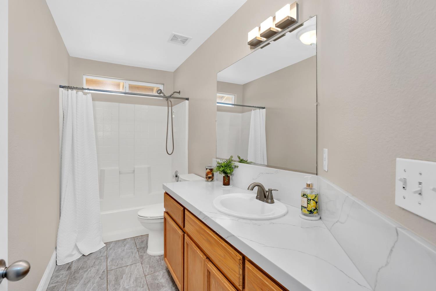 1406 San Rafael Street Los Banos, CA 93635 - Photo 25 of 35 a bathroom with a granite countertop sink a mirror a vanity and shower