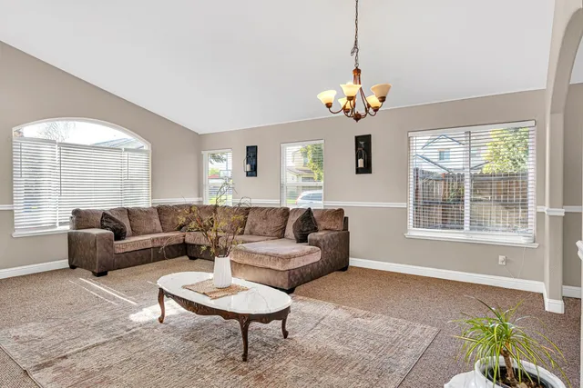 a living room with couch a dining table and a chandelier