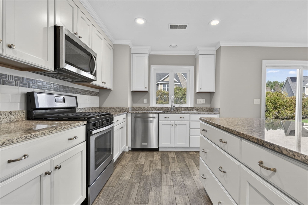 129 Acton Street, Unit 16 Maynard, MA 01754 - Photo 12 of 41 a kitchen with granite countertop white cabinets stainless steel appliances a sink and a window