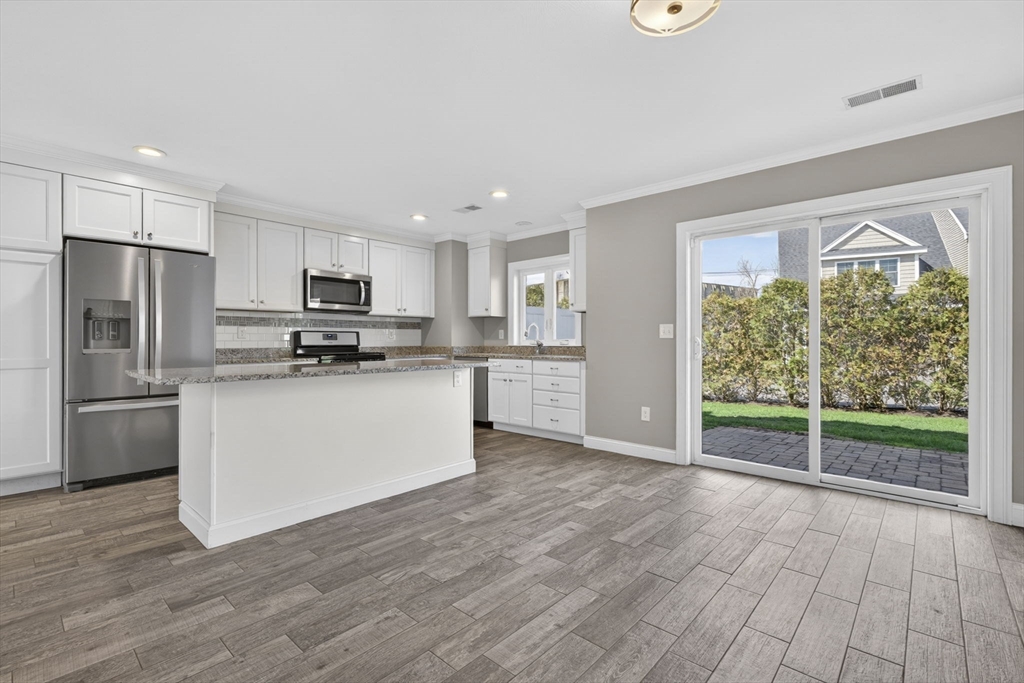 129 Acton Street, Unit 16 Maynard, MA 01754 - Photo 4 of 41 a kitchen with wooden floors white cabinets and stainless steel appliances