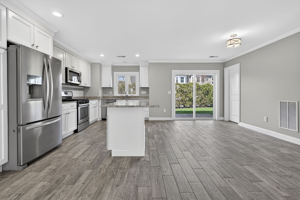 129 Acton Street, Unit 16 Maynard, MA 01754 - Photo 5 of 41 a kitchen with stainless steel appliances a refrigerator a sink dishwasher a stove and white cabinets with wooden floor