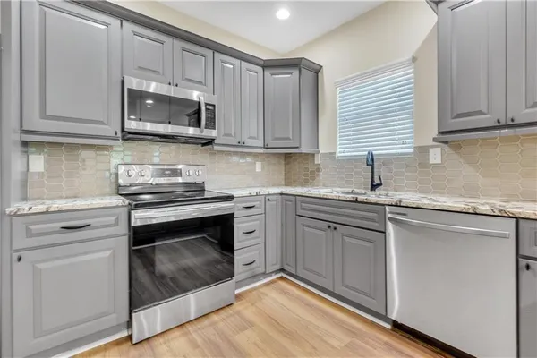 a kitchen with white cabinets appliances and a sink