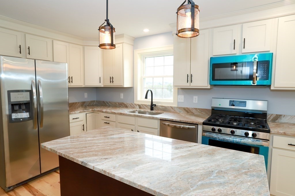 Lot 197 Stowell Road Ashburnham, MA 01430 - Photo 33 of 42 a kitchen with kitchen island granite countertop a stove a sink a refrigerator and wooden cabinets