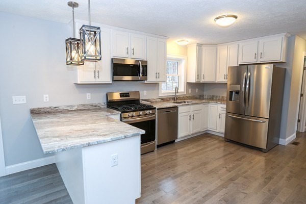 Lot 197 Stowell Road Ashburnham, MA 01430 - Photo 4 of 42 a kitchen with stainless steel appliances granite countertop a stove a sink dishwasher a refrigerator a microwave oven with cabinets and wooden floor