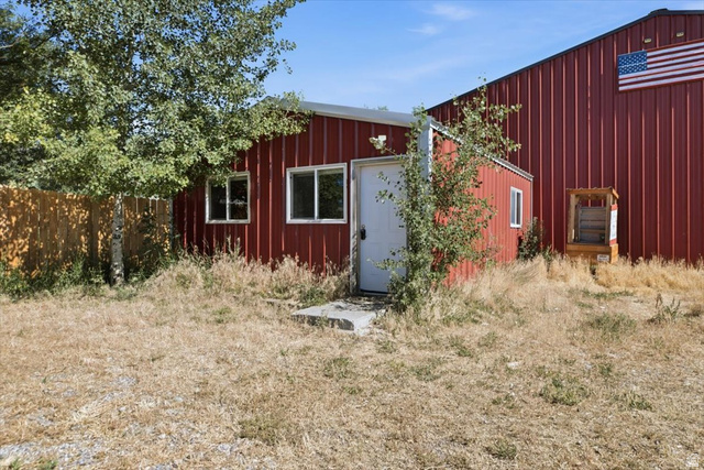 1634 West Arimo Road Arimo, ID 83214 - Photo 33 of 89 Red corrugated metal exterior featuring white trim windows and a white entry door