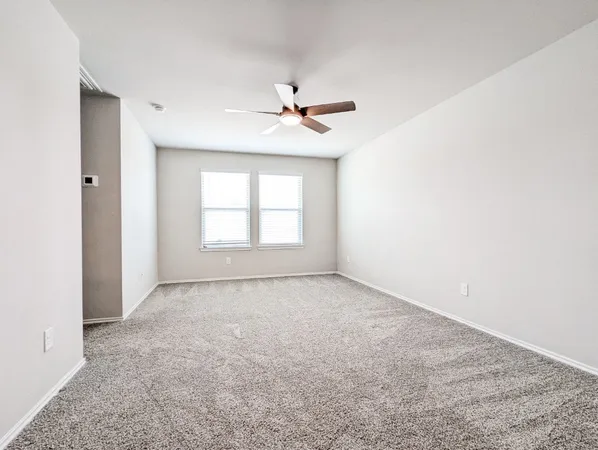 an empty room with chandelier fan and windows