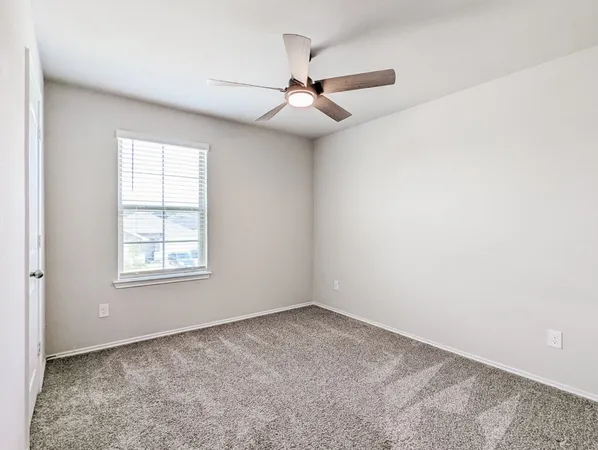 an empty room with a window and a fan