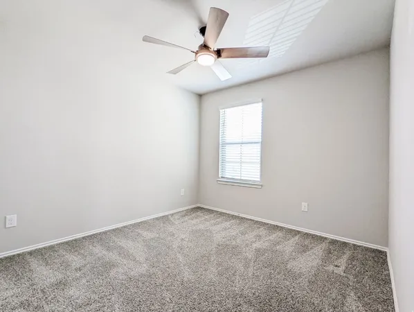 an empty room with a ceiling fan and window