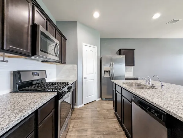 a kitchen with stainless steel appliances granite countertop a sink stove and refrigerator