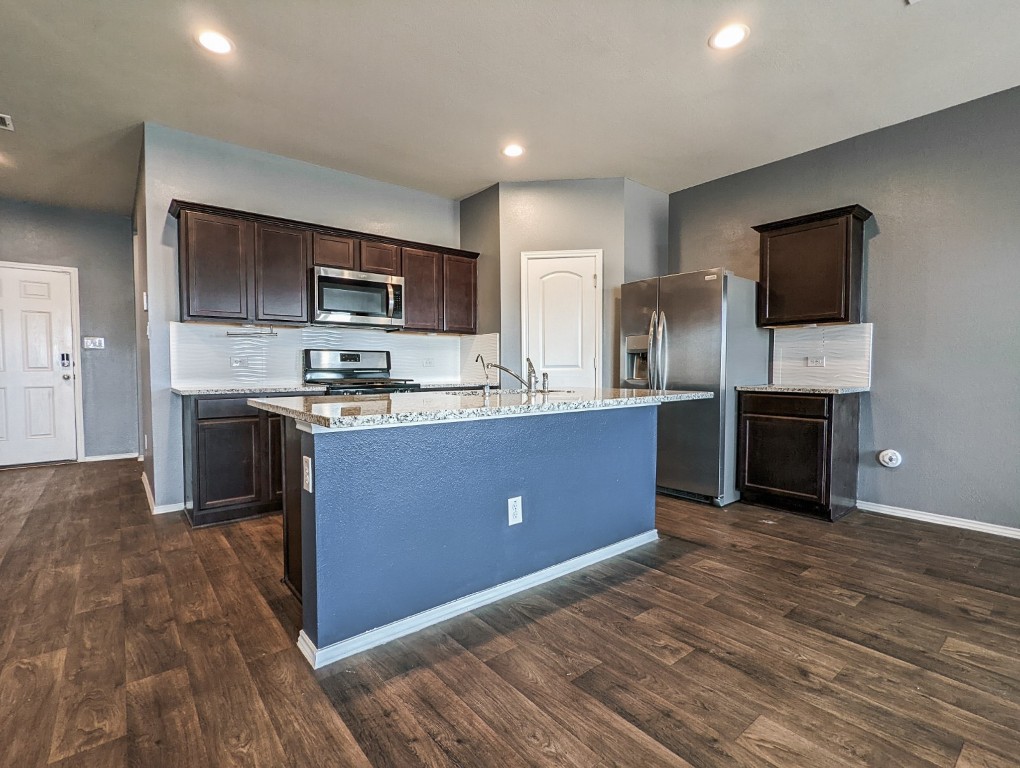 14541 Montclair Way Magnolia, TX 77354 - Photo 4 of 31 a kitchen with stainless steel appliances granite countertop a stove a sink dishwasher a refrigerator and a microwave oven with wooden floor