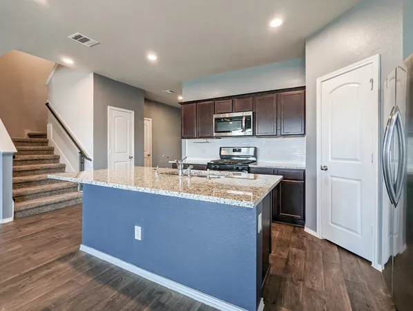 a kitchen with stainless steel appliances granite countertop a sink stove and refrigerator