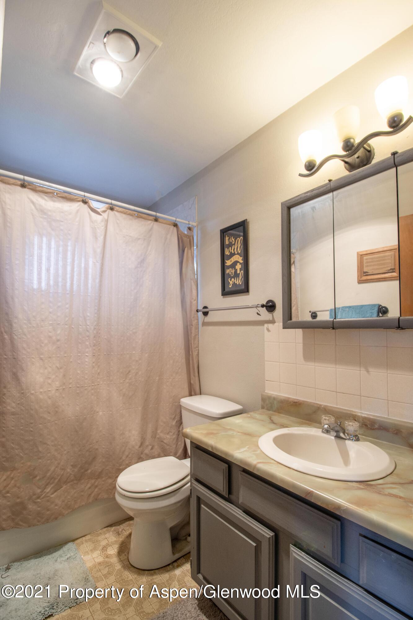 1002 Arnold Court Rifle, CO 81650 - Photo 8 of 15 a bathroom with a granite countertop sink toilet a mirror and a shower