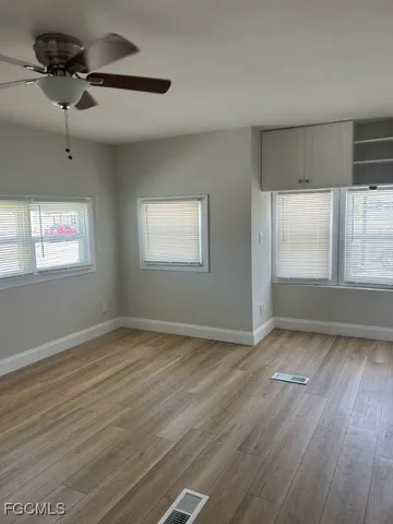 a view of an empty room with a window and wooden floor