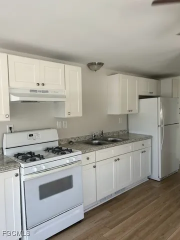 a kitchen with granite countertop white cabinets and white appliances