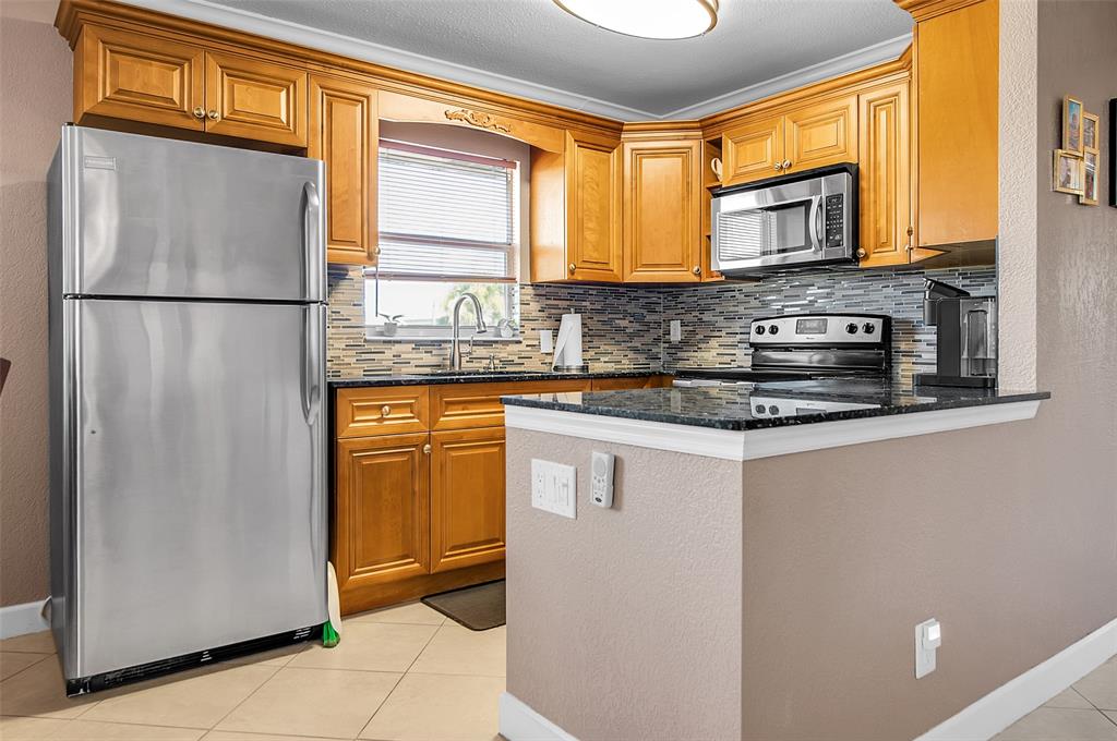 409 Brittany Drive, Unit 409 Delray Beach, FL 33446 - Photo 11 of 41 a kitchen with stainless steel appliances granite countertop a refrigerator a stove a sink and a microwave