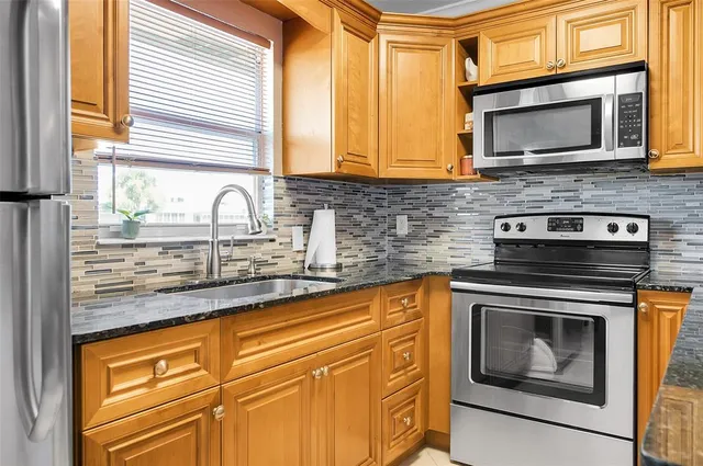 a kitchen with stainless steel appliances granite countertop a sink a stove microwave and cabinets
