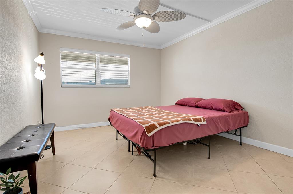 409 Brittany Drive, Unit 409 Delray Beach, FL 33446 - Photo 24 of 41 a bedroom with a bed and a chandelier