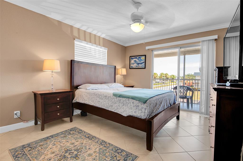 409 Brittany Drive, Unit 409 Delray Beach, FL 33446 - Photo 27 of 41 a bedroom with a bed and a chandelier