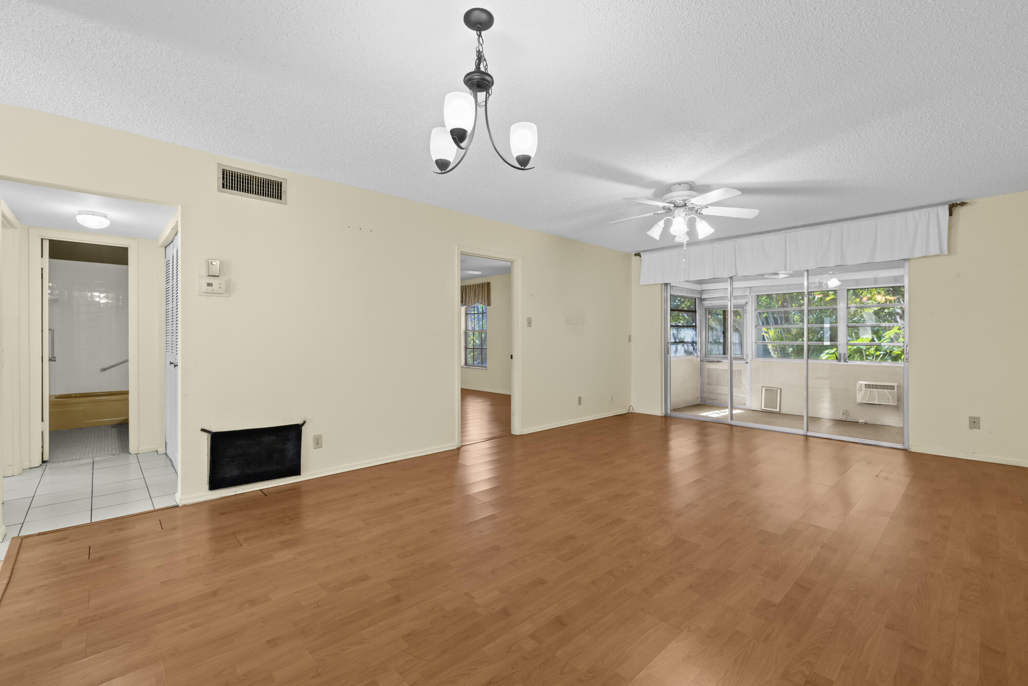251 Down E Lane Lake Worth, FL 33467 - Photo 7 of 22 a view of an empty room with wooden floor and a window