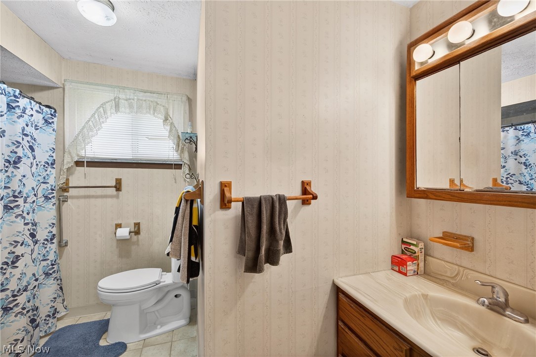 4404 Florida Street Perry, OH 44081 - Photo 16 of 24 Bathroom featuring a shower with shower curtain, light tile patterned flooring, vanity, and a textured ceiling