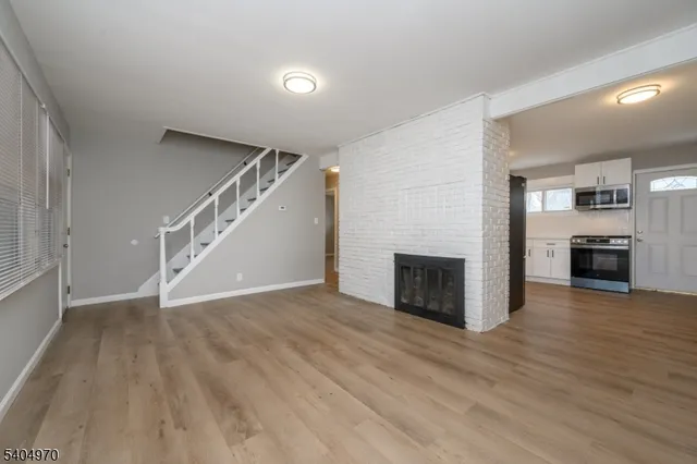 an empty room with wooden floor fireplace and windows