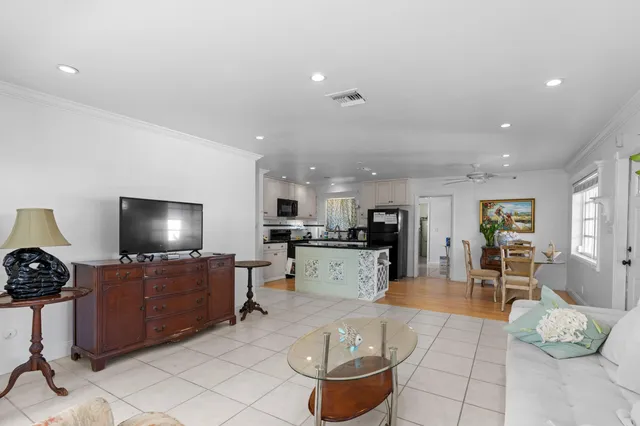 a kitchen with stainless steel appliances kitchen island granite countertop a refrigerator a stove top oven a sink dishwasher and white cabinets with wooden floor