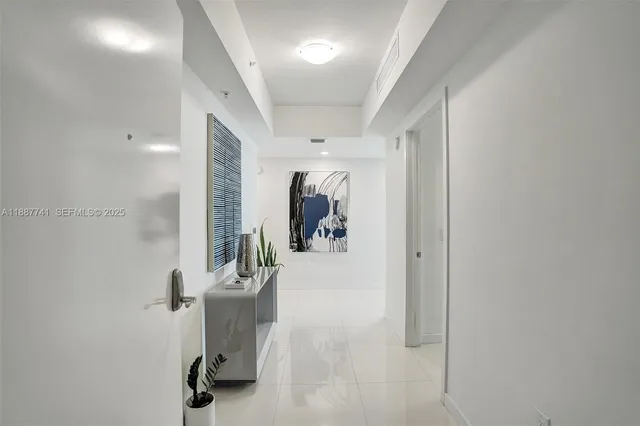 a view of a hallway with wooden floor and a bathroom