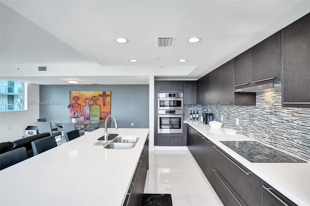 a large kitchen with stainless steel appliances kitchen island a large counter top a sink a stove and a refrigerator