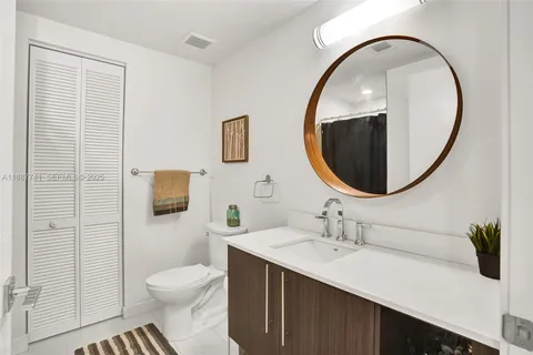 a bathroom with a sink a mirror a toilet and a window