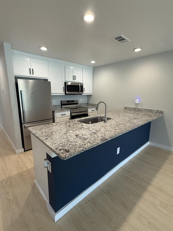 505 Thomas Street Terrell, TX 75160 - Photo 4 of 38 Kitchen featuring an island with granite-style countertops, stainless steel appliances, recessed lighting, white cabinetry, and wood-finish flooring