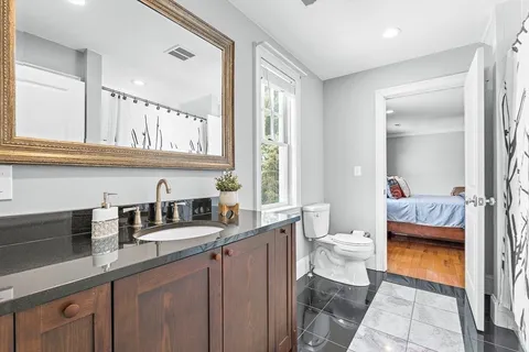 a en suite bathroom with a granite countertop sink and a mirror
