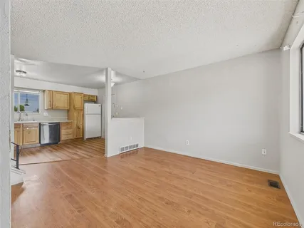 a view of empty room with kitchen and window