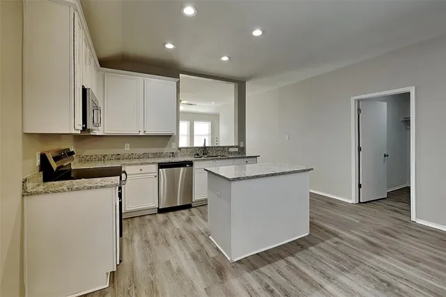 a kitchen with granite countertop a sink cabinets and wooden floor