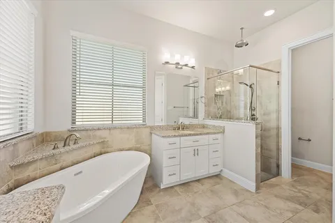 a spacious bathroom with a granite countertop tub sink shower and a mirror