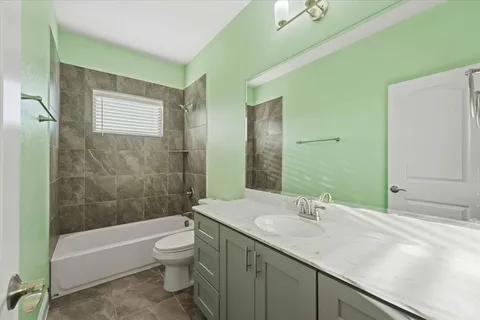 a bathroom with a granite countertop sink toilet a large mirror a bathtub and shower