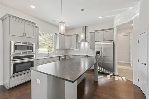 a kitchen with a center island refrigerator wooden floor and appliances