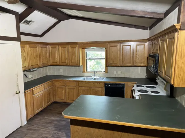 a kitchen with granite countertop a sink window and refrigerator