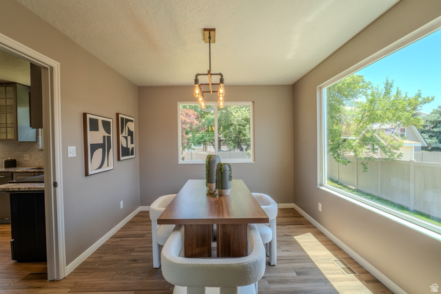 11957 Noelle Road Sandy, UT 84092 - Photo 12 of 38 Dining area featuring wood-finish flooring, a contemporary chandelier, and a large picture window
