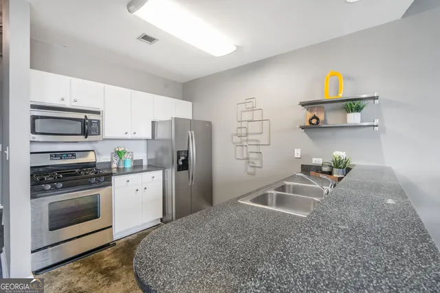 a kitchen with stainless steel appliances granite countertop a stove a sink and a refrigerator