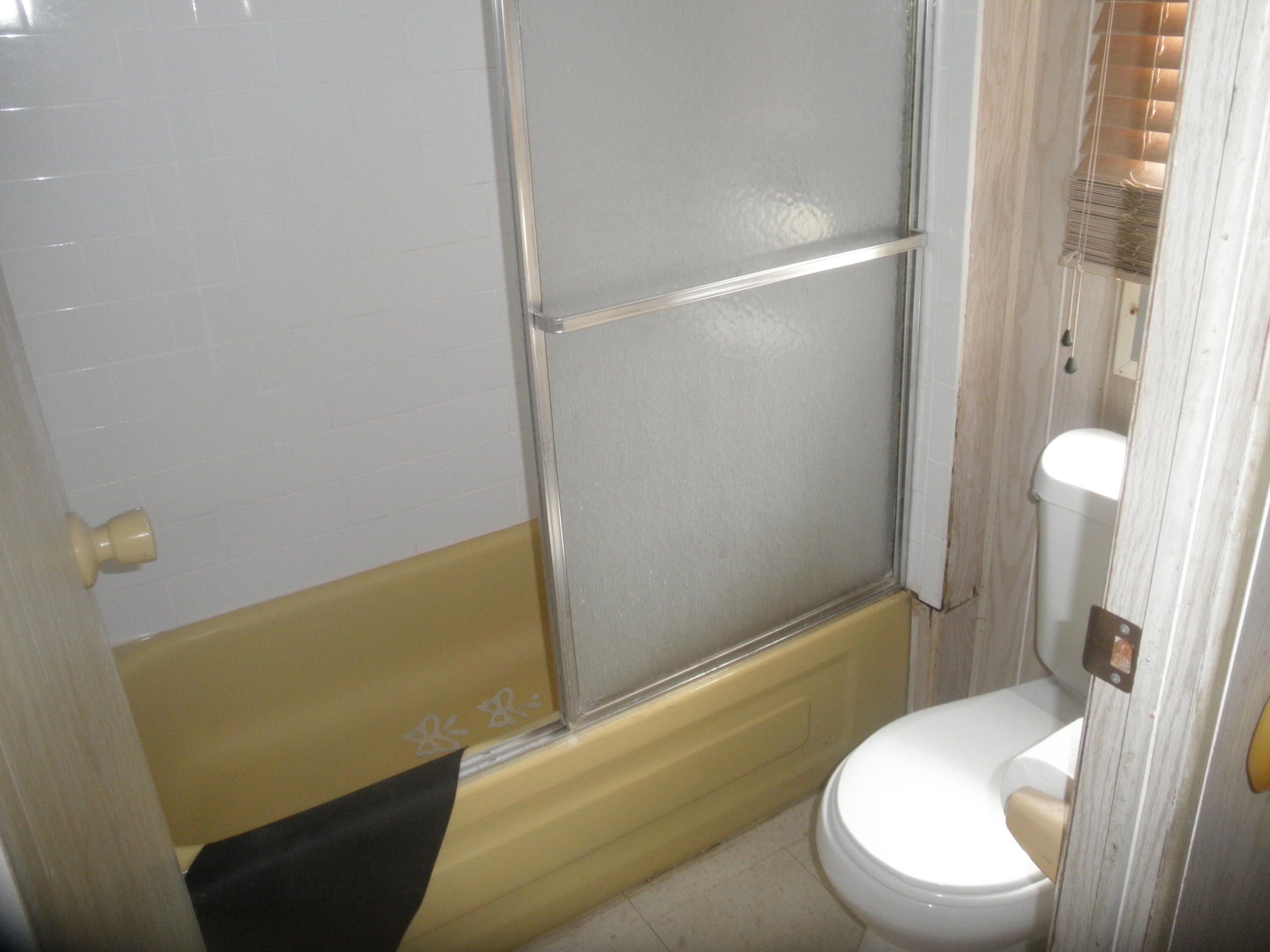 4544 Sunset Ranch Road West Palm Beach, FL 33415 - Photo 6 of 10 a white toilet sitting next to a bathroom sink and a shower